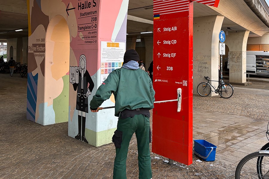 Mitarbeiter reinigt Schild am Hauptbahnhof.