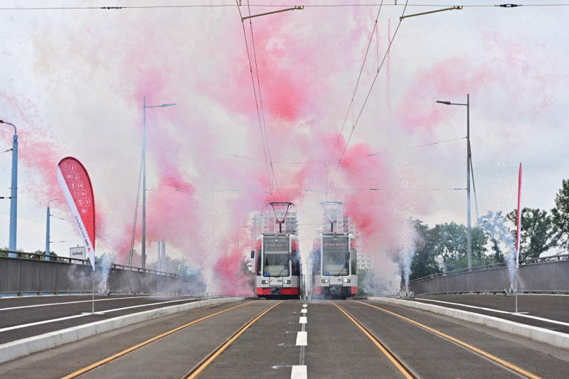 Zwei Bahnen fahren parallel über die Brücke, im Hintergrund Feuerwerk.