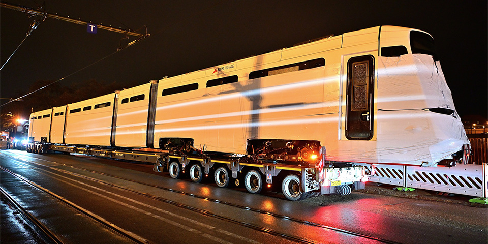 Die neue TINA-Bahn wird mit einem großen Tieflader angefahren.