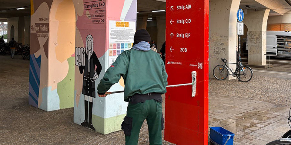 Mitarbeiter reinigt Schild am Hauptbahnhof.