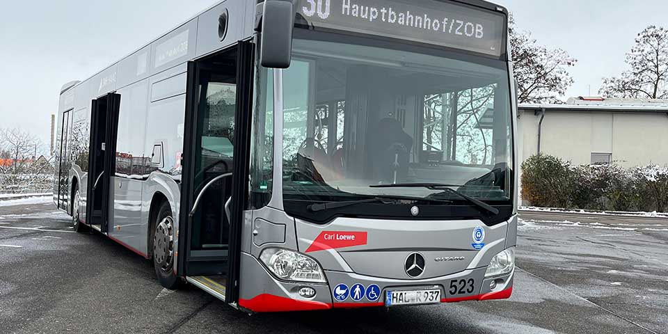 Moderner Stadtbus der Linie 30 mit geöffneter Tür und Zielanzeige '30 Hauptbahnhof/ZOB' auf einem Parkplatz.