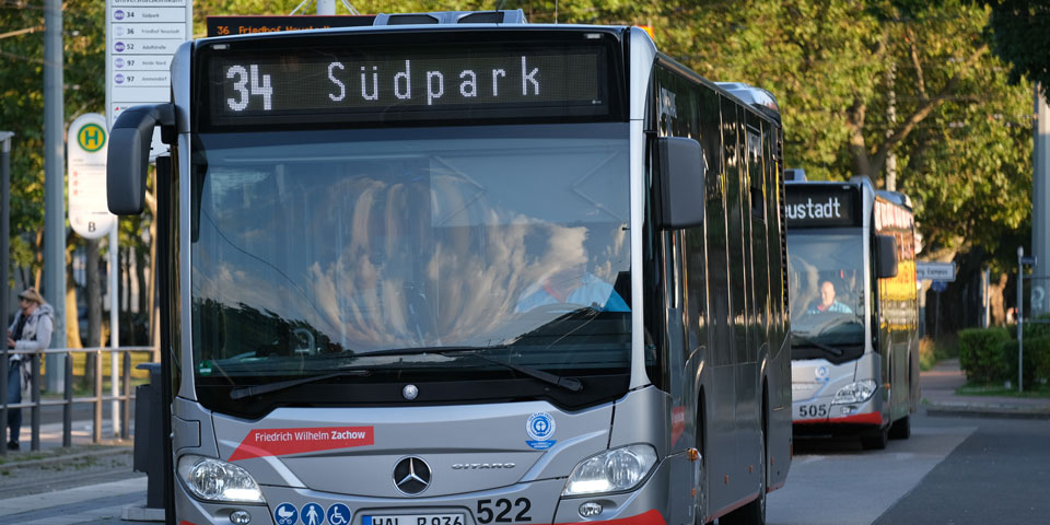 Buslinie 34 mit Zielanzeige 'Südpark' steht an einer Haltestelle, dahinter ein weiterer Bus.