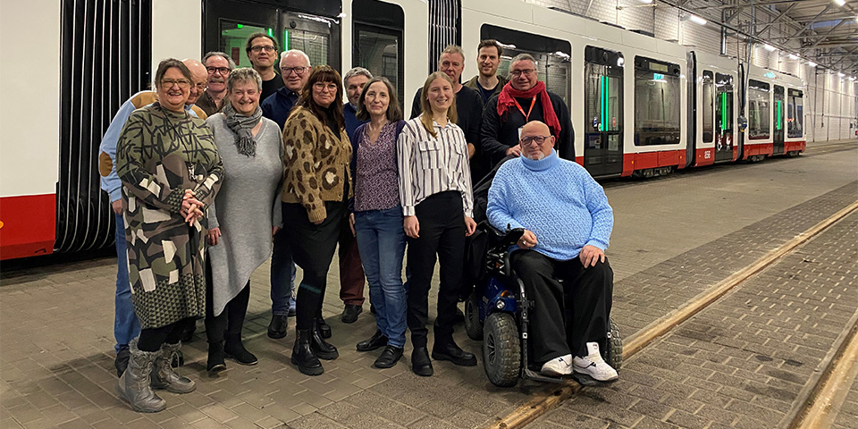 Mitglieder des Fahrgastbeirats vor einer TINA Bahn.