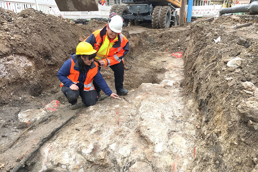 Archäologin Ines Valhaus (links) und die Projektverantwortliche der HAVAG Heike Knopf schauen sich den Fund des Stadttores genauer an. 