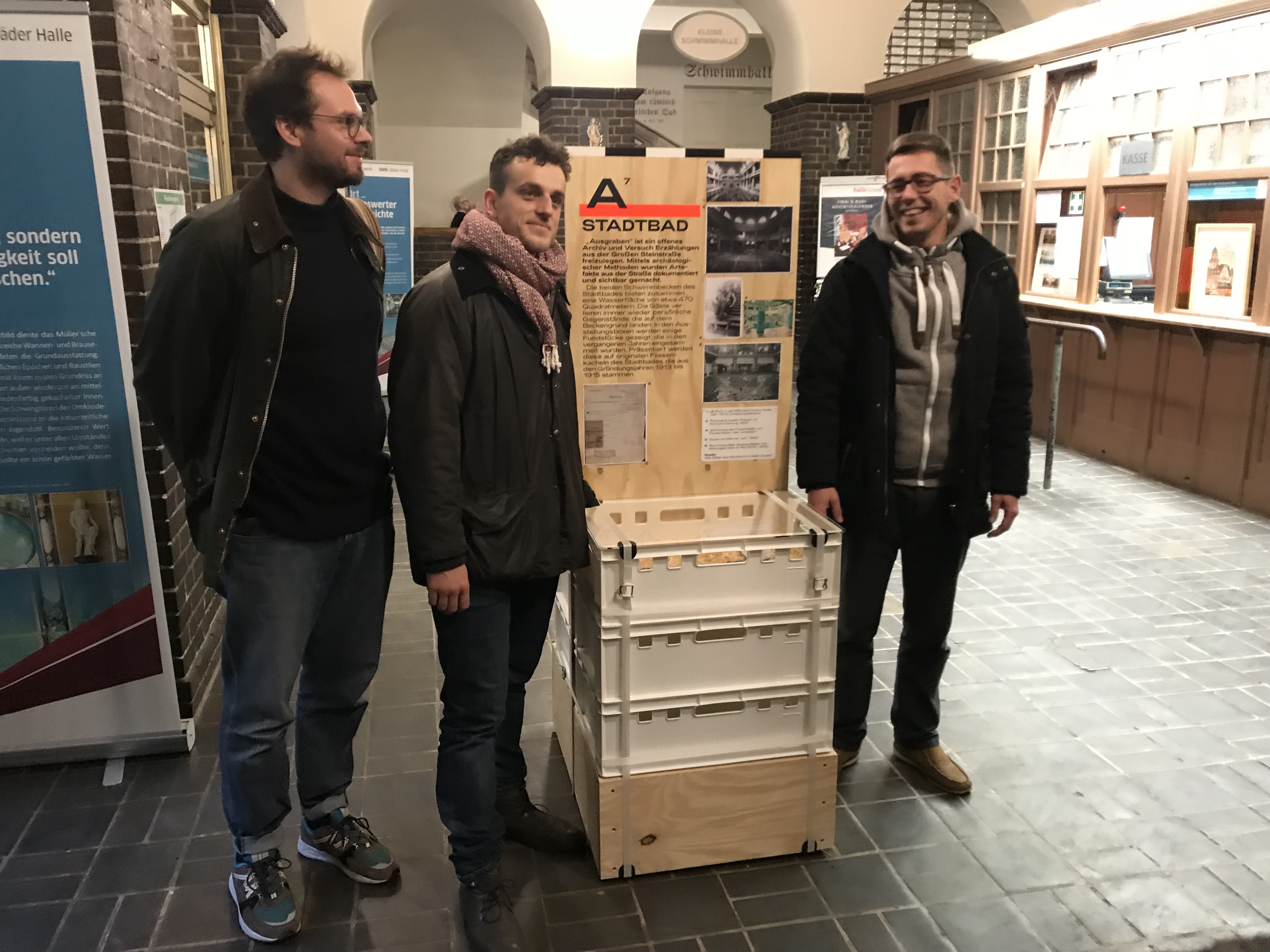 Ausstellungsmacher Benjamin Schief und Gregor Müller mit Ricardo Noll vom Stadtbad an der Ausstellungskiste im Stadtbad.   