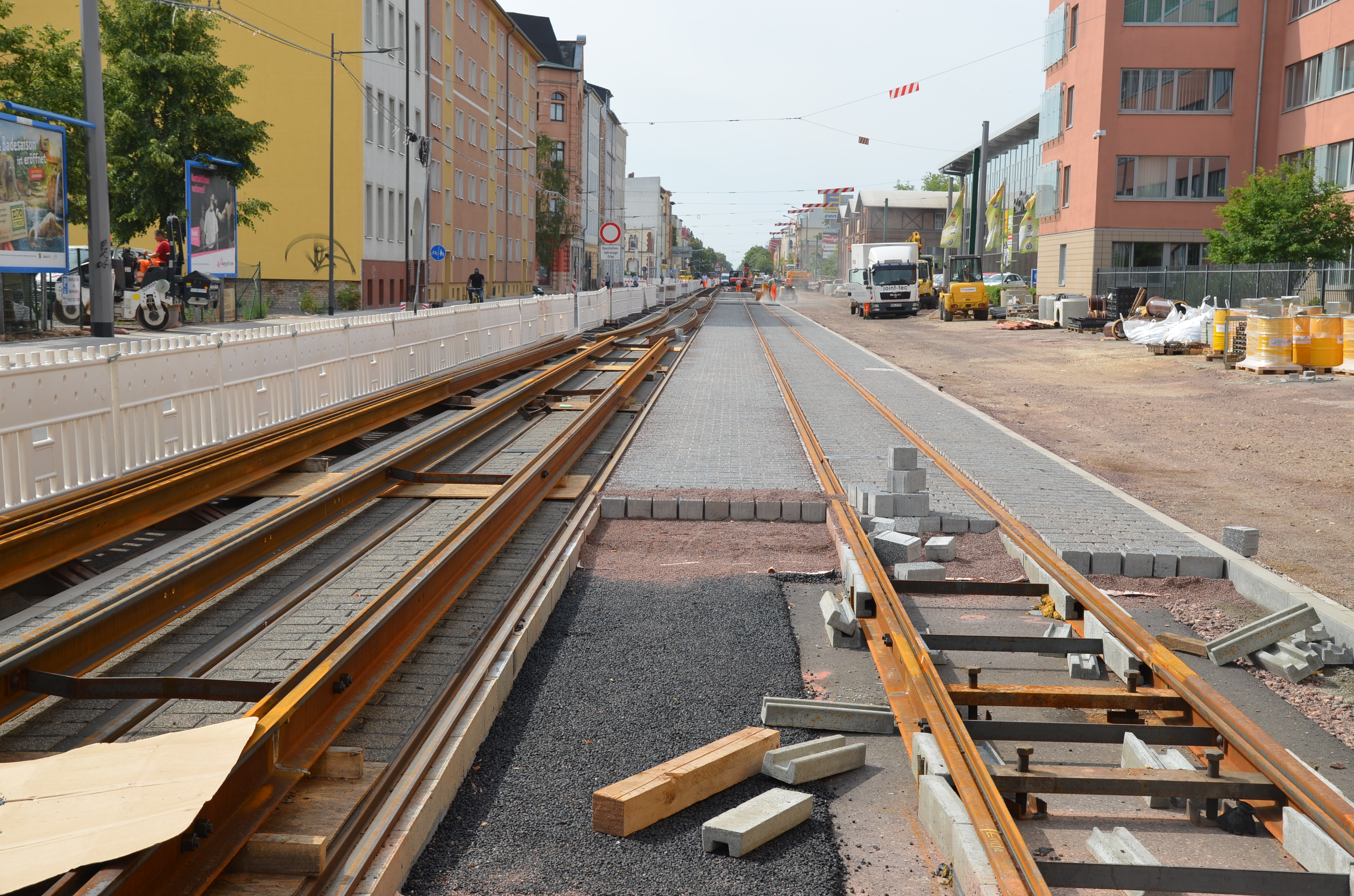 Das Bild zeigt die Baustelle in der Merseburger Straße. Hier sind schon auf zwei Fahrbahnen neue Straßenbahnschienen verlegt, jedoch fehlen noch Pflastersteine dazwischen.