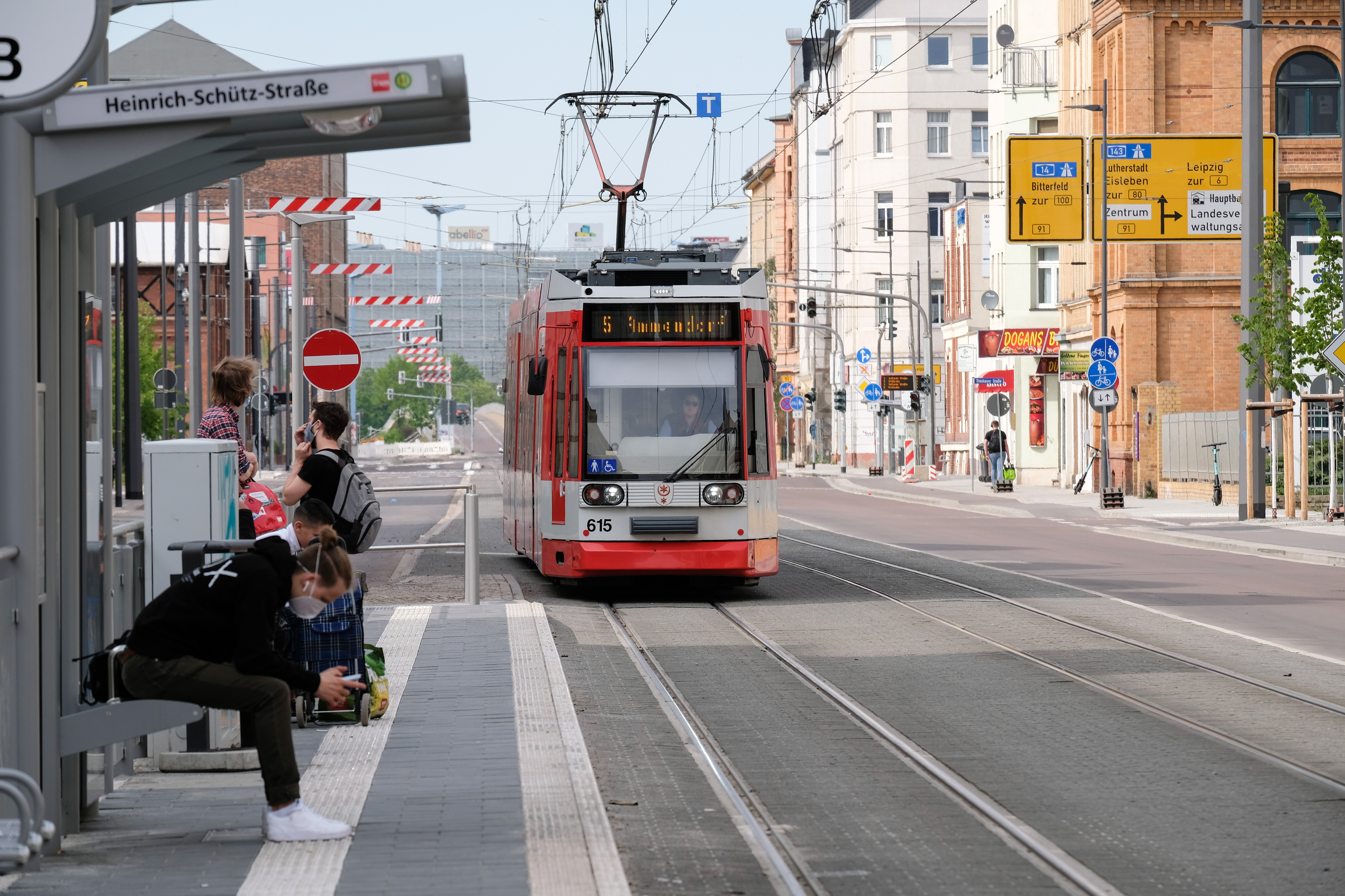 Am linken Bildrand befindet sich die Haltestelle "Heinrich-Schütz-Straße", an die gerade eine rote Straßenbahn der HAVAG heranfährt.