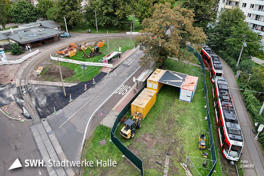 Eine Luftaufnahme der Endtstelle. Rechts steht eine rote Straßenbahn der HAVAG. Auf der Grünfläche nebenan stehen gelbe Baucontainer.