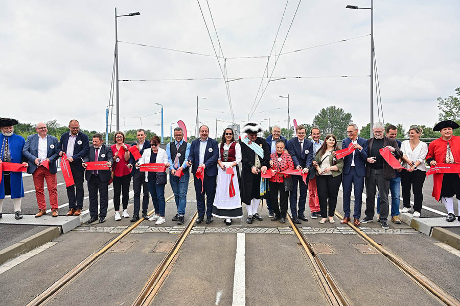 Zahlreiche Akteurinnen und Akteure durchtrennen gemeinsam das Band und geben die Brücke frei.