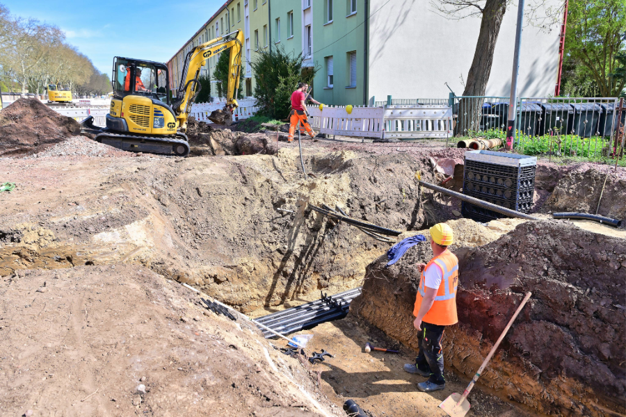 Bauarbeiter stehen in einem Graben der Baustelle.