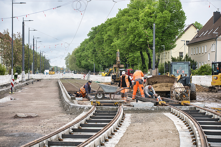 Bauarbeiter arbeiten an Straßenbahngleisen. 