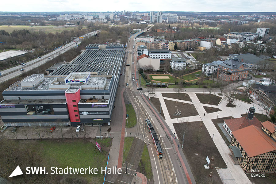 Blick von Oben auf das große Gebäude Wohncentrum Lührmann mit angrenzenden Schienenverlauf der Straßenbahnen.