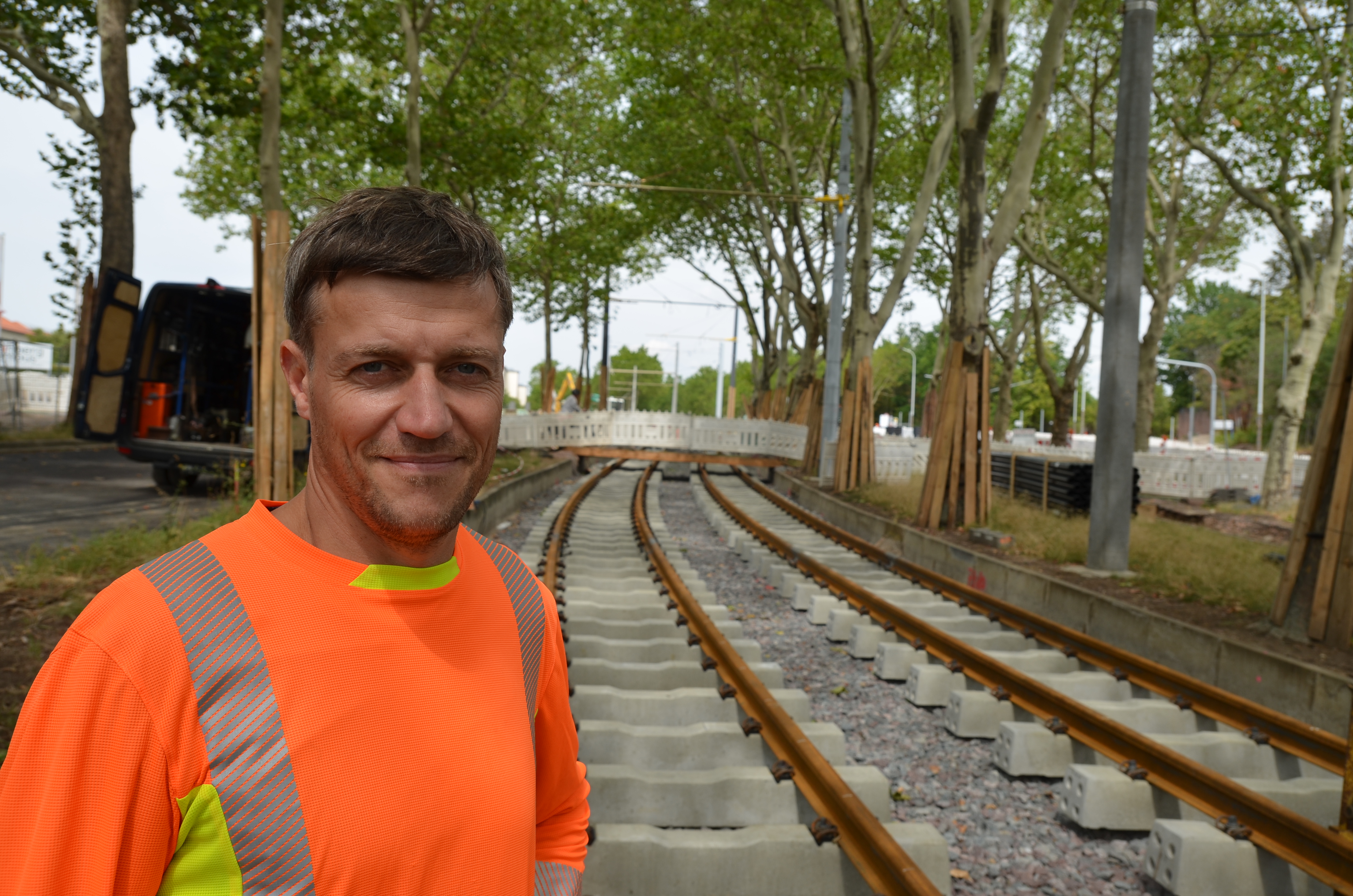 Dieses Bild ist ein Porträt des Bauoberleiters, Jörg Linke, der auf den neu verlegten Straßenbahnschienen steht.