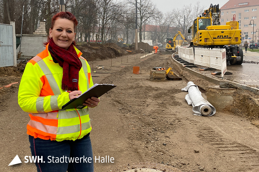 Eine Frau (Projektleiterin) steht auf einer Baustelle und lächelt in die Kamera.