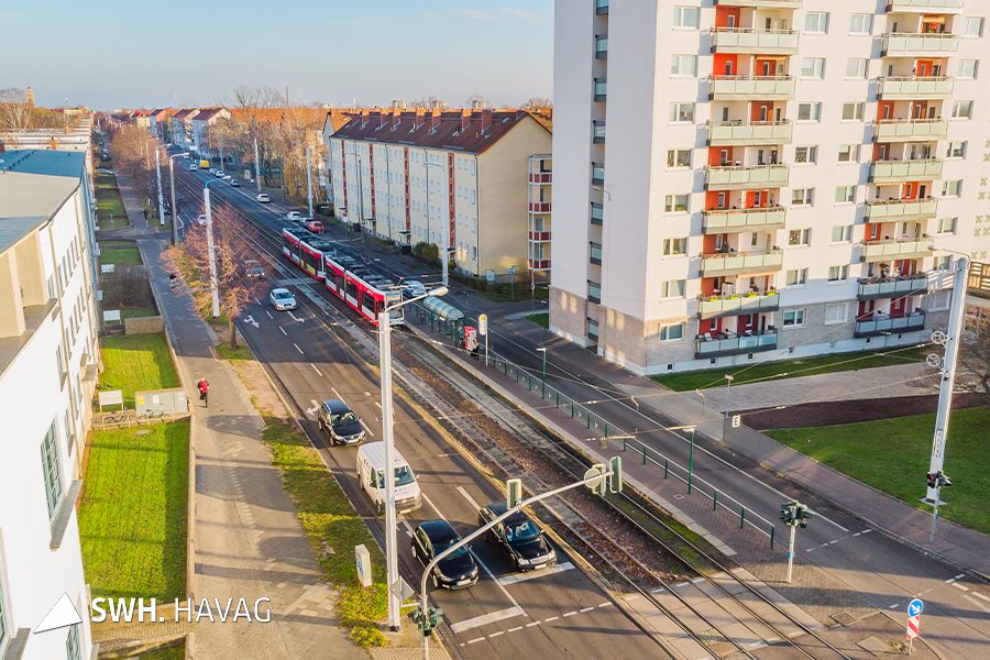 Eine Luftaufnahme der Paul-Suhr-Straße. Vier Autos stehen an einer Ampel. Weitere folgen. Eine Straßenbahn steht an der Haltestelle. 
