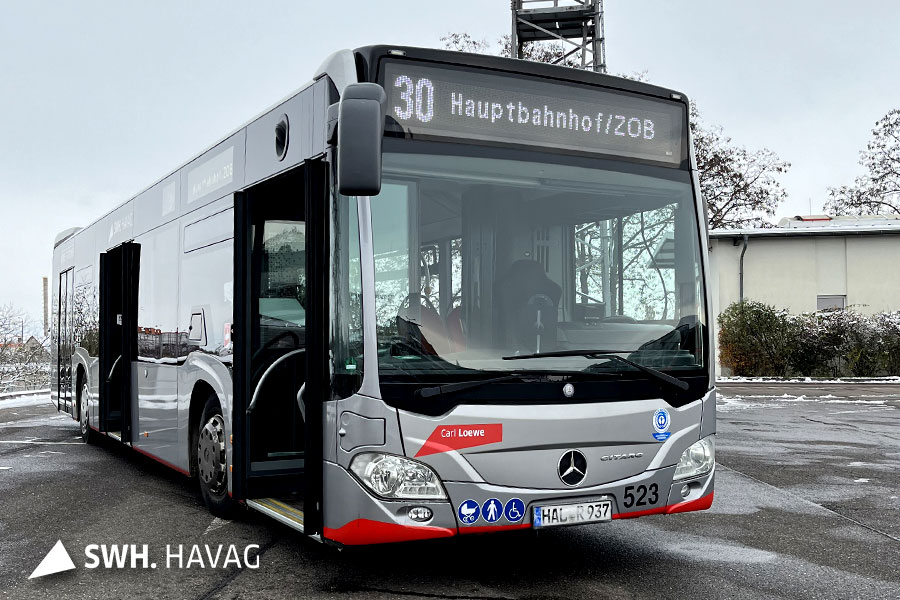 Eine Aufnahme eines silbernen Busses der HAVAG auf einem Platz. Um den Bus liegt ein bisschen Schnee. Der Bus hat die Zielaufschrift "30 Hauptbahnhof/ZOB".