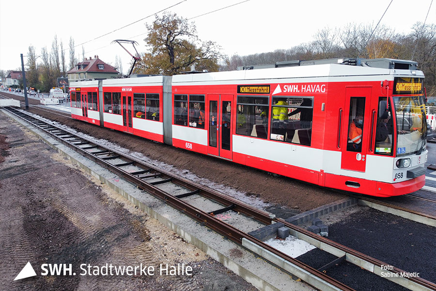 Eine Aufnahme von oben: eine rote Straßenbahn der HAVAG fährt von links nach rechts durch das Bild. im Vordergurnd ist noch ein weiteres Gleis zu sehen. Ringsherum sieht es aus wie auf einer Baustelle.