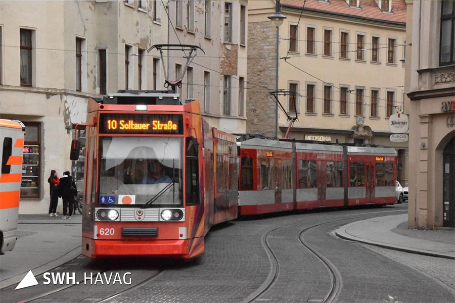 Die rote Straßenbahn der Linie 10, mit der Zielaufschrift "10 - Soltauer Straße" fährt durch eine Straße direkt auf den Fotografen zu. Links und rechts der Bahn stehen Häuser. Die Bahn fährt eine leichte Kurve.