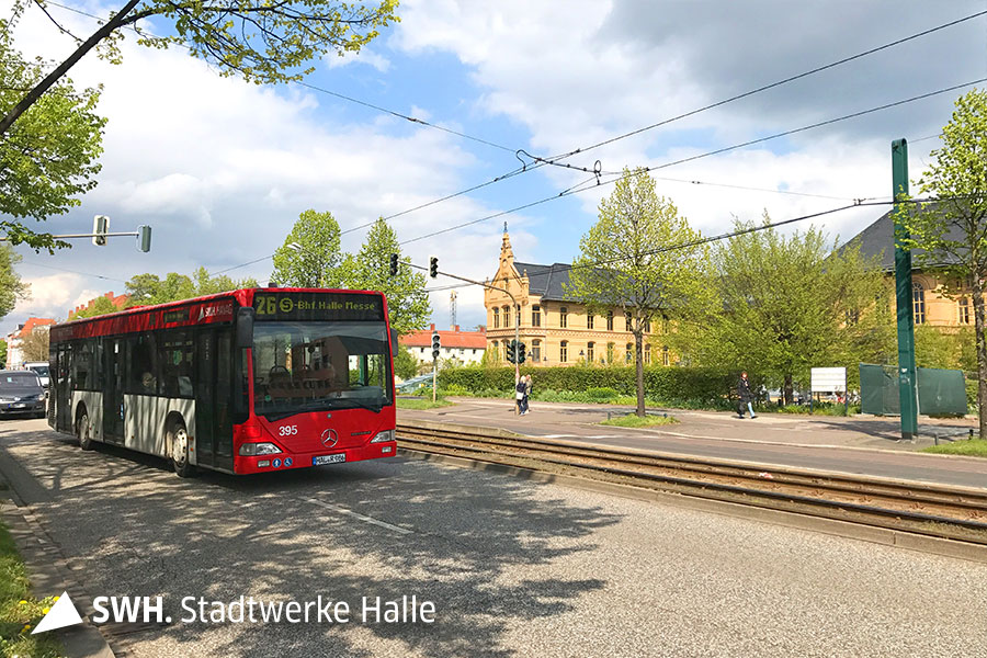 Das Foto zeigt eine Straße, auf der ein roter Bus der HAVAG und mehrere Autos unterwegs sind. In der Mitte der Straße befinden sich Straßenbahngleise.