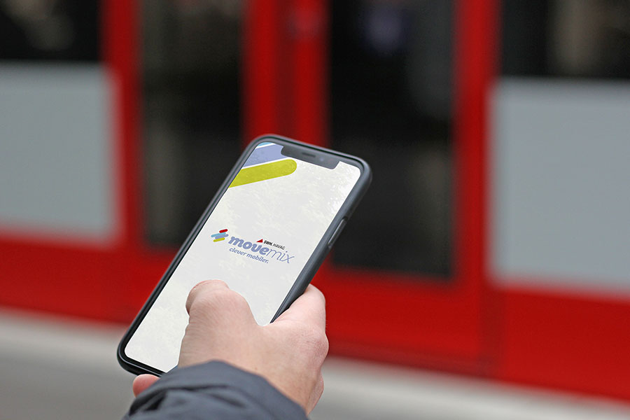 Eine Person hält in der rechten Hand ein Smartphone und darauf zu sehen ist die App movemix.