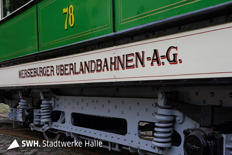 Eine Nahaufnahme eines alten Straßenbahnwaggons. Die obere Hälfte des Bildes ist grün, darauf steht die Zahl 78. Darunter ist ein weißer Streifen auf dem mit schwarzer Schrift "Merseburger Überlandbahnen -A.-G.".
