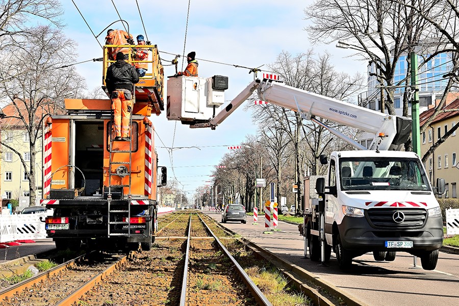 Mitarbeiter auf Turmwagen montieren Leitungen.