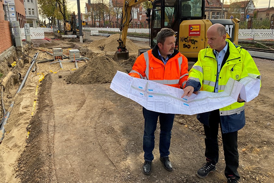 Zwei Mitarbeiter halten Bauplan.