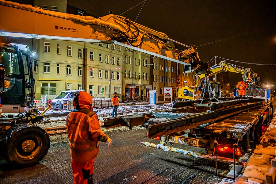 Kran legt Schiene auf Anhänger ab.