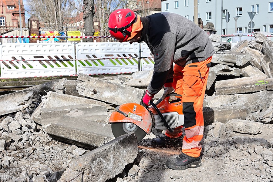 Arbeiter trennt Stahlbeton mit Trennschleifer.