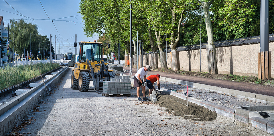 Zwei Bauarbeiter bauen Straßenborde.
