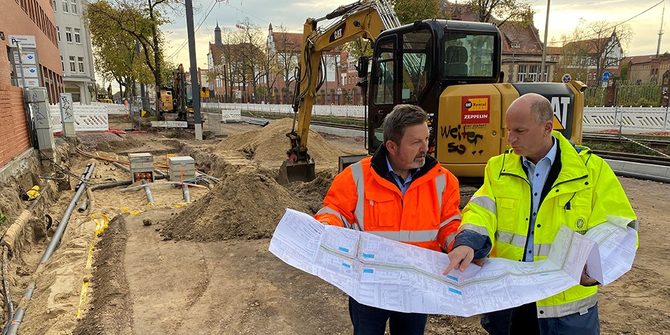 Zwei Mitarbeiter halten Bauplan.