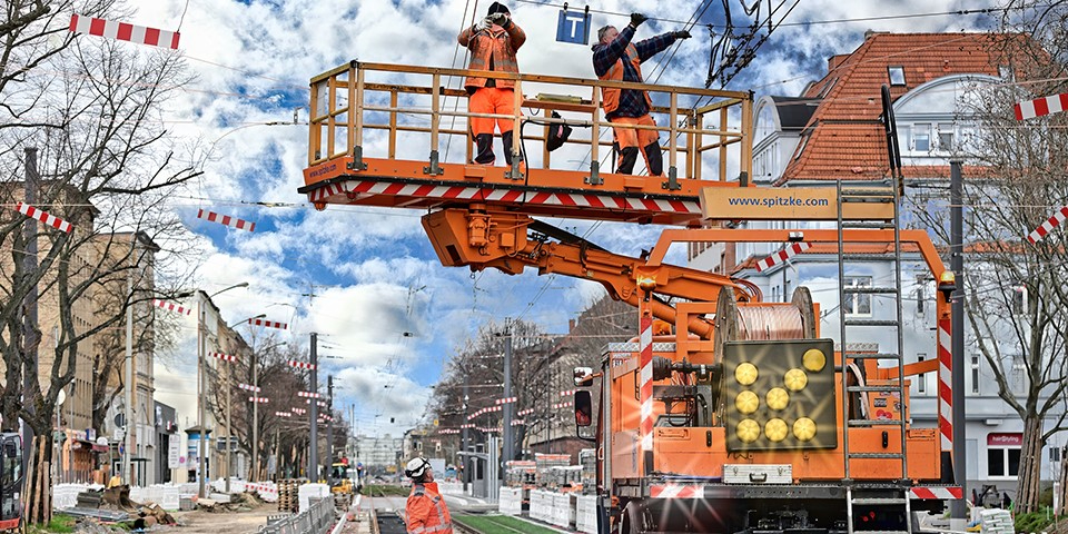 Zwei Mitarbeiter auf Turmwagen kontrollieren Leitugnen.