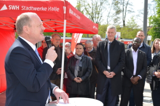 Verkehrsministers des Landes Sachsen-Anhalt Thomas Webel hat ein Mikro in der Hand und spricht zu allen Gästen. Im Hintergrund steht ein rotes Stadtwerke-Zelt.
