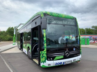 Ein grün beklebter E-Bus steht auf einer Straße. Als Zielschrift steht "E-Busse für Halle".