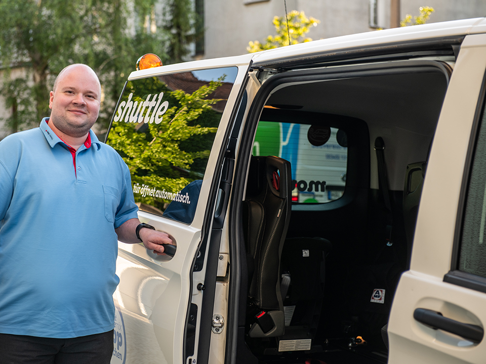 Ein Fahrer steht an einem movemix_shuttle.