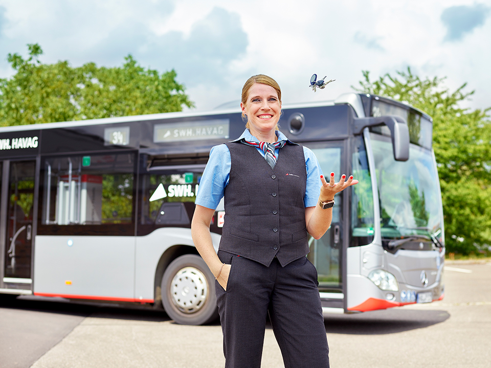 Eine Busfahrerin steht vor einem HAVAG-Bus.